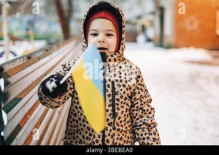 Ukrainisches Kind draußen in Poltawa, Ukraine mit Flagge des Landes. Flüchtlingskrise in Europa. Invasion der russischen Armee, stoppt den Krieg. Stockfoto