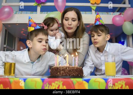 Familie bläst Kerzen auf Geburtstagskuchen Stockfoto