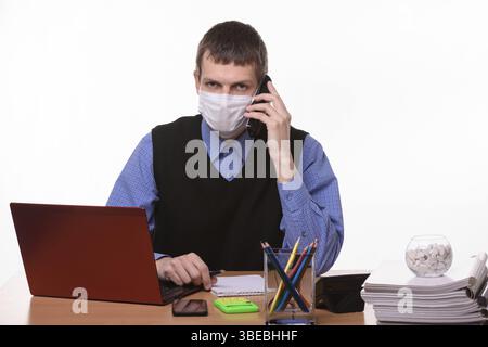 Der Angestellte in einer medizinischen Maske telefoniert und schaut in den Rahmen Stockfoto