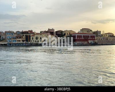 Kreta, Chania Altstadt. Geschäfte und Restaurants am Wasser, ein Seemuseum und Gebäude mit traditioneller Architektur bei Sonnenuntergang, bewölktem Himmel Stockfoto