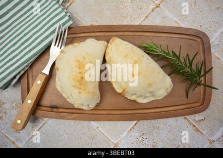 Goldene Calzone-Pizza, serviert auf einem Holzbrett Stockfoto