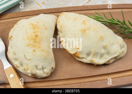 Goldene Calzone-Pizza, serviert auf einem Holzbrett Stockfoto