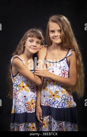 Zwei Schwestern aus verschiedenen Altersgruppen auf schwarzem Hintergrund Stockfoto