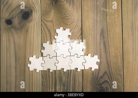 Puzzleteile sind pyramidenförmig auf einem Holztisch angeordnet. unternehmensgewerkschaftskonzept. Stockfoto
