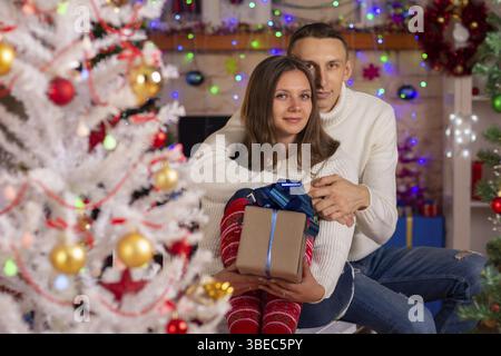 Ein Paar in der Liebe mit Geschenken in der Nähe eines Weihnachtsbaums Stockfoto