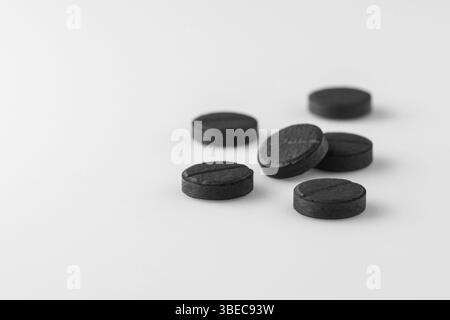 Mehrere schwarze medizinische Aktivkohlepillen auf weißem Hintergrund. Isoliert Stockfoto