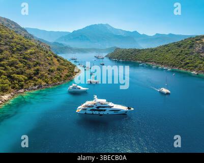 Blick aus der Vogelperspektive auf wunderschöne Yachten und Boote auf dem Meer bei Sonnenuntergang im Sommer. Gemiler Island in der Türkei. Blick von oben auf Luxusyachten, Segelboote, klares Blau mit Stockfoto