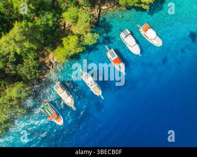 Blick aus der Vogelperspektive auf wunderschöne Yachten und Boote auf dem Meer am sonnigen Sommertag. Fethiye Lagunen, Türkei. Blick von oben auf die Bucht, Luxusyachten, Segelboote, Clear bl Stockfoto