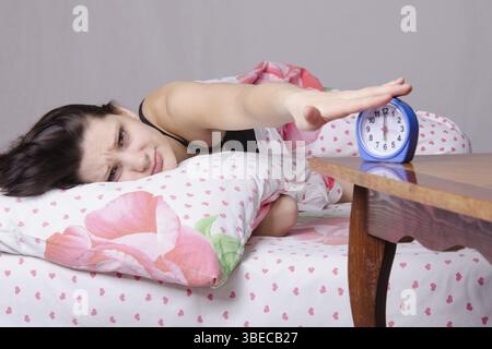 Frau schlafend im Bett, neben einen Wecker auf dem Tisch, die Plätze an den 06:00 Stockfoto