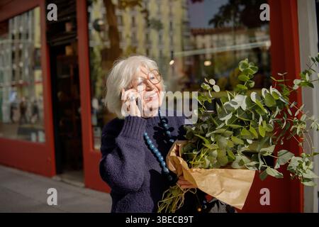 Eine ältere Frau, die draußen am Handy spricht Stockfoto