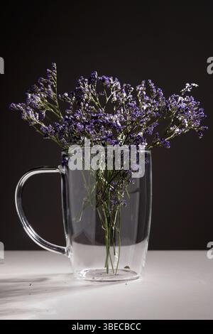 Getrocknete Fliederblüten im Glasbecher Stockfoto