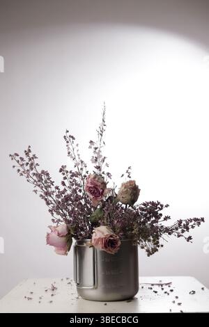 METALLBEHÄLTER MIT ROSEN UND GETROCKNETEN BLUMEN Stockfoto