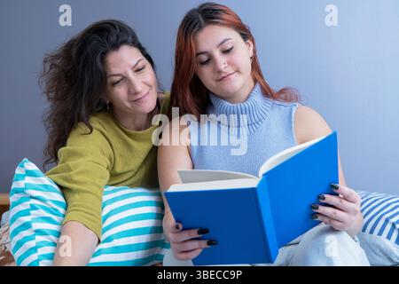 Ein friedlicher Moment, während Mutter und Tochter ein Buch in einer gemütlichen Umgebung lesen. Stockfoto