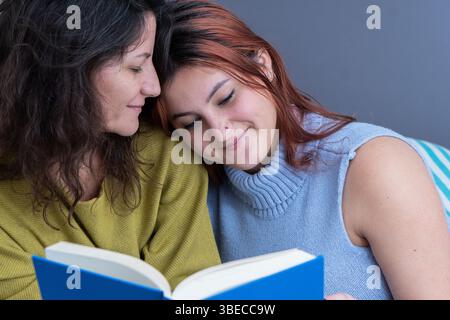 Mutter und Tochter in einem liebevollen Moment, zusammen ein Buch zu lesen an einem entspannenden Tag. Stockfoto
