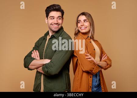 Ein fröhliches und lebhaftes junges Paar steht hinter den Kulissen und präsentiert stolz ihre stilvollen und modischen Outfits vor einem lebendigen und warmen Hintergrund Stockfoto