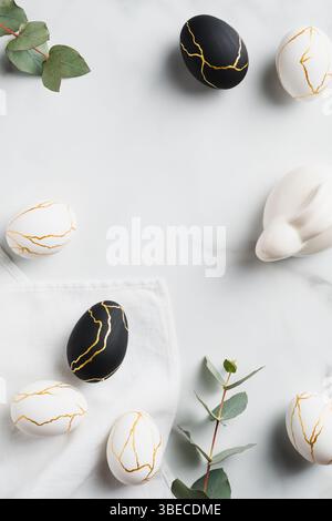 Elegante Ostern flach Lay Komposition. Luxuriöse Ostereier verziert Gold, Osterhase Kaninchen, Eukalyptus auf Marmortisch. Draufsicht. Stockfoto