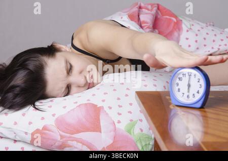 Frau schlafend im Bett, neben einen Wecker auf dem Tisch, die Plätze an den 06:00 Stockfoto