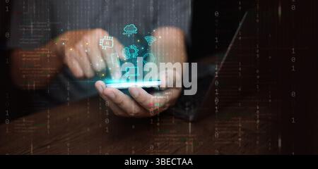 Digitale Technologie und Cloud-Computing: Konzept. Ein Mann, der mit seinem Smartphone und Laptop Informationen und Daten erstellt, speichert, verarbeitet und kommuniziert Stockfoto