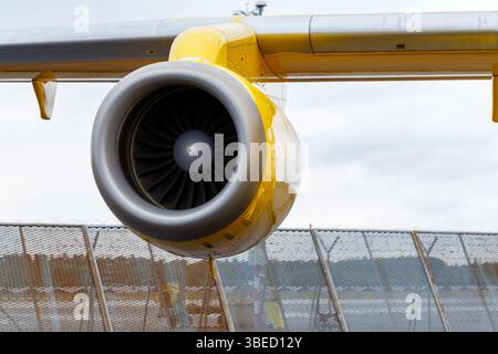 Nürnberg, Deutschland - 25. Mai 2025: Nahaufnahme eines gelb-grauen Flugzeugtriebwerks an einem Flügel. Der Motor dominiert den Rahmen gegen Wolken Stockfoto
