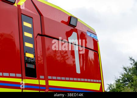 Nürnberg, Deutschland - 25. Mai 2025: Nahaufnahme der Seite eines roten Feuerwehrwagens mit gelben und blauen Streifen, mit weißer Nummer „1“ und diversen li Stockfoto