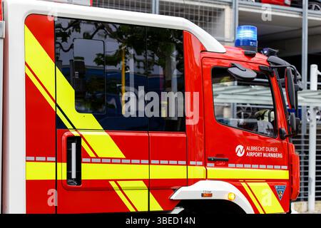 Nürnberg, Deutschland - 25. Mai 2025: Nahaufnahme der Seiten- und Frontseite eines rot-weißen Feuerwehrwagens mit gelben Streifen, mit Fenstern, blauem Licht, Stockfoto
