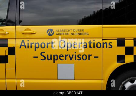 Nürnberg, Deutschland - 25. Mai 2025: Nahaufnahme eines gelben Fahrzeugs mit schwarzen karierten Mustern und blauem Schriftzug, der darauf hinweist, dass es zum Flughafen O gehört Stockfoto
