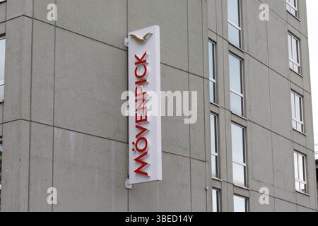 Nürnberg, Deutschland - 25. Mai 2025: Ein Movenpick Hotelschild in rot, vertikal auf einem grauen Betongebäude mit sichtbaren Fenstern montiert. Stockfoto