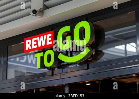 Nürnberg, Deutschland - 25. Mai 2025: Außenaufnahme des „REWE To Go“-Schilds mit rot und grün beleuchteten Buchstaben auf einem dunklen Rahmen. Surveilla Stockfoto