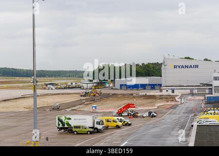Nürnberg, Deutschland - 25. Mai 2025: Flughafenszene mit Bau-, Dienstwagen- und Ryanair-Gebäude unter bewölktem Himmel. Stockfoto