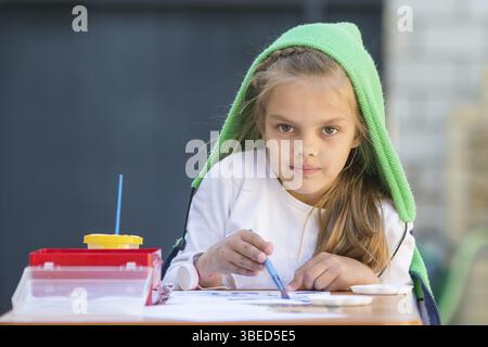 Zufrieden Mädchen zieht Farben am Tisch und schaute auf den Rahmen Stockfoto