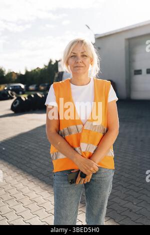 Nahporträt einer Ingenieurin mit orangefarbener Weste. Weibliche LKW-Fahrerin. Stockfoto