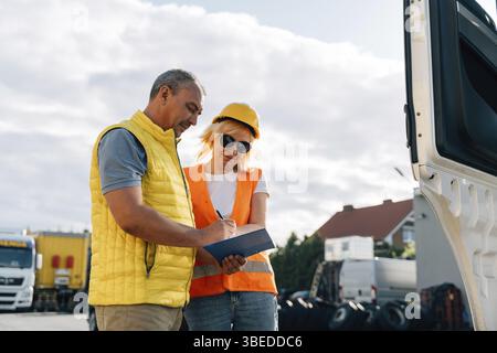 Reife Frau und Mann im Frachtlager, LKW-Fahrer-Lieferkontrolle. Stockfoto