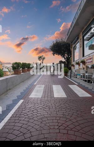 Kopfsteinpflasterstraße in Positano, Italien bei Sonnenuntergang mit Scooter Rider Stockfoto