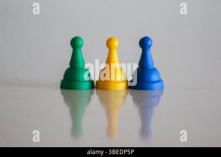 Drei Spielfiguren in Grün, Gelb und Blau, die die Farben der gabunischen Nationalflagge darstellen. Ein einfaches und symbolisches visuelles Konzept. Stockfoto
