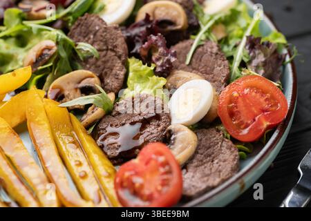 Warmer Salat mit saftigem gegrilltem Rindfleisch, gebratenem Pfeffer, Erdpilzen, frischem Gemüse, hart gekochtem Ei, und würzige Balsamico-Soße. Gesunde Gourmet-Diss Stockfoto