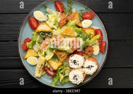 Meeresfrüchte Caesar Salat mit Garnelen, Kirschtomaten, Sushi-Brötchen mit Lachs und Frischkäse, serviert auf Teller. Restaurant-Menü-Konzept und gesundes Low- Stockfoto