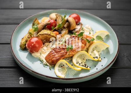 Gegrillter gekochter Lachsfisch mit gebackenem Gemüse und Pilzen auf Teller im Restaurant. Gesundes Essen, leckeres Gericht zum Abendessen. Kopierbereich Stockfoto
