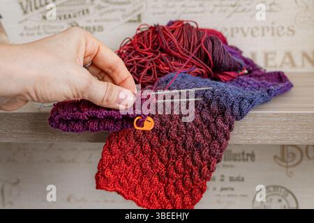 Stricknadeln in der Hand einer Frau. Gestrickte Elemente. Selbst gemachte warme Socken. Strickmuster. Hochwertiger Wollfaden. Winterkleidung. Weihnachtsgeschenk. Stockfoto