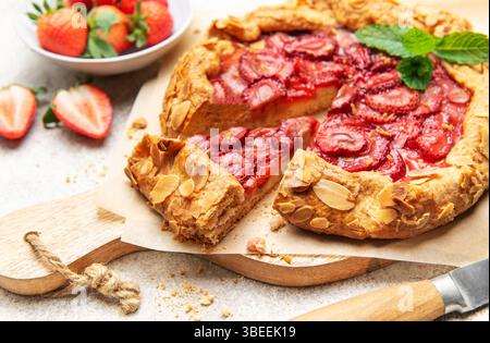 Frisch gebackene Erdbeergalette, dekoriert mit Mandelflocken und Minzblättern, mit einem Ausschnitt Stockfoto