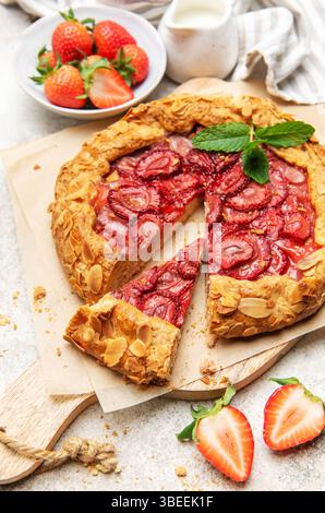 Frisch gebackene Erdbeergalette, dekoriert mit Mandelflocken und Minzblättern, mit einem Ausschnitt Stockfoto