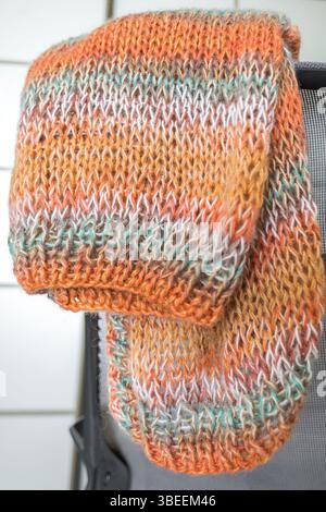 Farbenfrohe Strickjacke aus Mohair in warmen Farben mit einem Knäuel Garn. Strickmode. Herbst- und Wintergarderobe. Gemütliches Zuhause. Warme Sachen. Handwerkliches Produkt Stockfoto