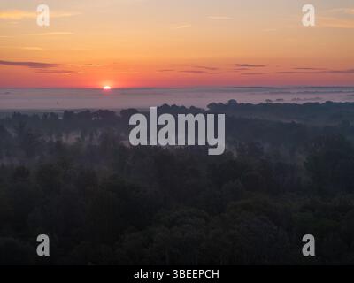 Blick aus der Vogelperspektive auf Sonnenaufgang und Morgennebel über einer Waldlandschaft im Lowland Stockfoto
