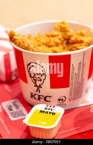 Padua, Italien - 15. April 2025: KFC ist eine beliebte Fast-Food-Kette, bekannt als Kentucky Fried Chicken. Viele heiße Flügel oder Streifen KFC-Hühnchen im Eimer Stockfoto