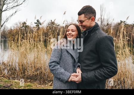 Ein Paar genießt einen romantischen Moment am See an einem bewölkten Tag im Herbst Stockfoto