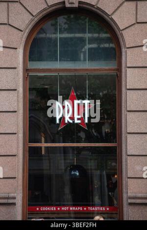 Ein Pret-Schaufenster in London zeigt Markenschilder mit einem Sternlogo. Die Steinfassade verleiht der städtischen Café-Szene einen klassischen Touch. Stockfoto