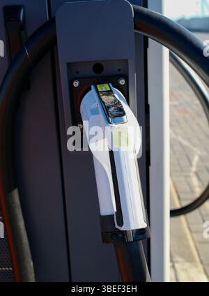 Nahaufnahme des weißen Ladeanschlusses für Elektrofahrzeuge, der an den EV-Ladeanschluss angeschlossen ist Stockfoto