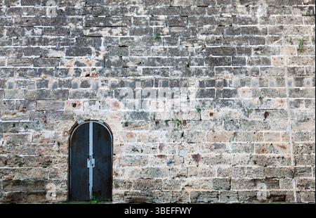 Eiserne Tür in einer alten, antiken Wand. Stockfoto