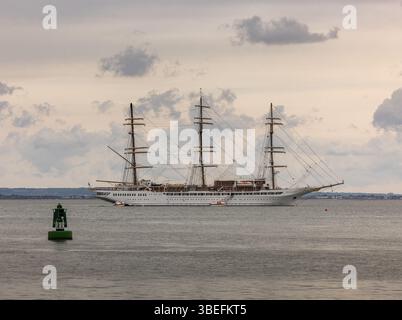 Ein viermastiges Segelschiff liegt vor der Küste nahe der Isle of Wight, Großbritannien, mit bewölktem Himmel und Navigationsoje im Vordergrund. Stockfoto