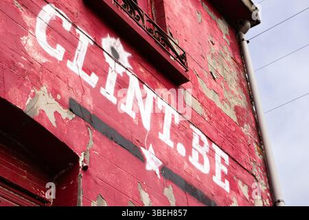 Alte rote Wand mit verblasstem Schriftzug und abblätternder Farbe in einer urbanen Umgebung, die das Wesen der historischen Architektur einfängt Stockfoto