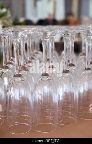 Viele umgedrehte Sektflöten, die ordentlich auf einem braunen Stoff angeordnet sind, elegante, schmalstielige Gläser, die normalerweise zum Servieren von Sekt verwendet werden Stockfoto